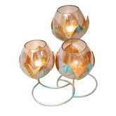 Modern piece of art with metal leaves in antique gold finish with three amber glass candle holders